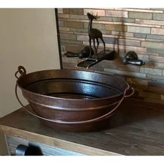 a large metal tub sitting on top of a wooden counter next to a faucet