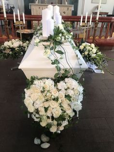 white flowers and greenery are arranged on the altar