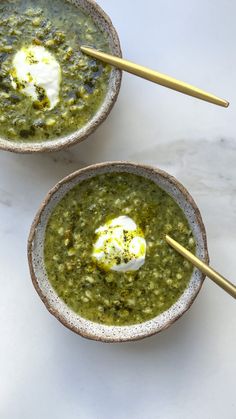 two bowls filled with green soup and topped with an egg