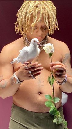 a man with dreadlocks holding a white bird on his chest and roses in his hands