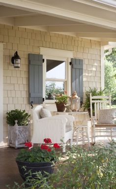 a porch with chairs, tables and potted plants