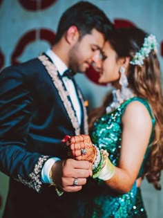 a man and woman are dressed in green outfits, holding each other's hands