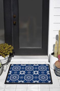 a blue door mat sitting on top of a tiled floor next to potted plants