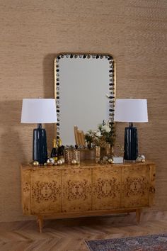 a wooden dresser topped with a mirror and two lamps