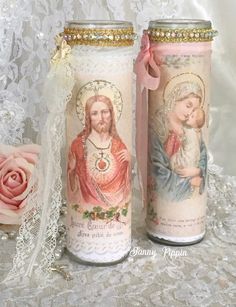 two candles decorated with images of jesus and mary are sitting on a lace tablecloth