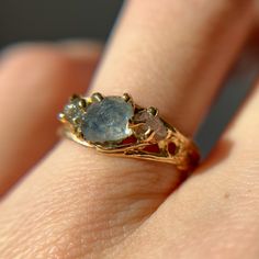 a woman's hand with a ring on it that has two stones in the middle