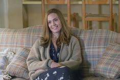 a woman sitting on top of a couch with her legs crossed