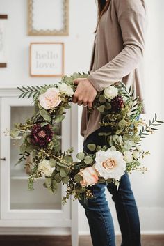 a woman holding a wreath with flowers on it