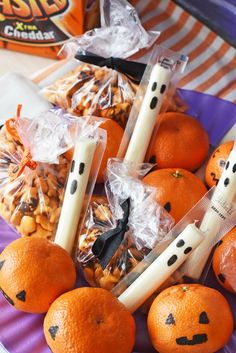 some oranges with candles and candy sticks in them sitting on a purple paper plate