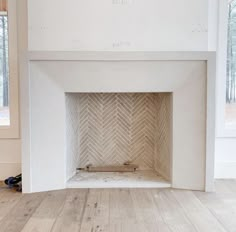 an empty fireplace with white paint and wood flooring