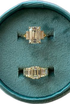 two yellow gold rings with baguettes in a green velvet case on display for sale