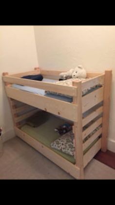 a wooden bunk bed sitting next to a wall with a stuffed animal on top of it