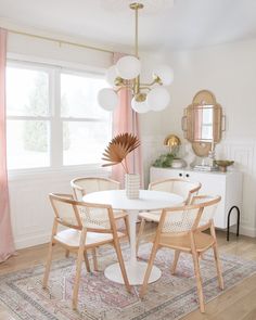 a dining room table with chairs and a rug in front of the window is shown