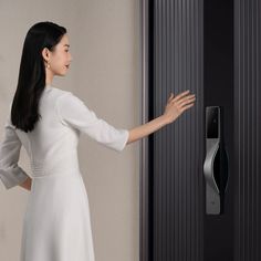 a woman in a white dress is touching the door handle on a black and silver door