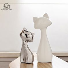 two white vases sitting on top of a wooden table