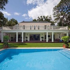 a large house with a pool in front of it and trees around the back yard