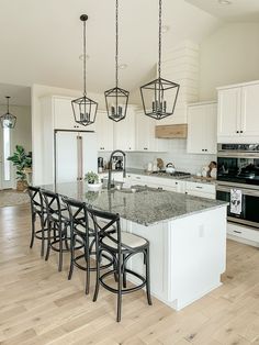 a kitchen with white cabinets and an island in the middle is surrounded by black barstools