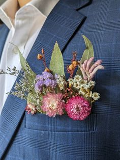 a man wearing a blue suit with flowers and leaves on his lapel flower pin