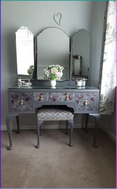 an ornate vanity with mirror and stool in the corner next to a flower vase on top of it