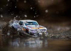 a toy car sitting on top of a wet floor next to a pile of rocks