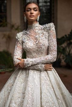 a woman wearing a wedding dress with long sleeves and an intricate pattern on the skirt