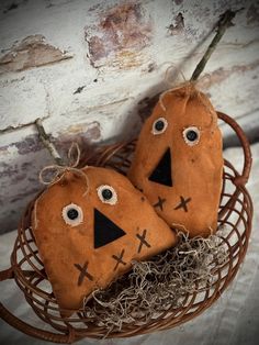 two stuffed pumpkins with eyes and noses sitting in a basket