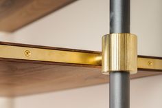 a close up of a metal pole with a wooden shelf in the background and a gold object on it