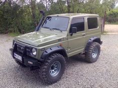 a green jeep is parked in the gravel