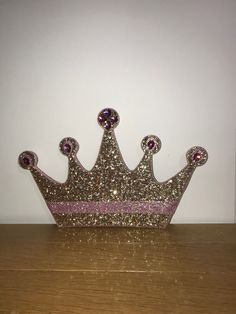 a glittered crown sitting on top of a wooden table next to a white wall