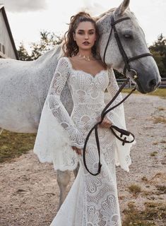 a woman in a white dress standing next to a horse