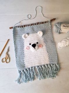 a crocheted polar bear on a blanket next to yarn and scissors