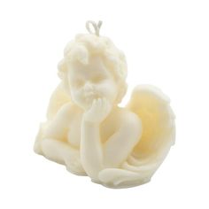 a white candle with a little angel sitting on it's side and holding its hand to her mouth