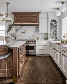 a kitchen with marble counter tops and white cabinetry, along with wooden flooring