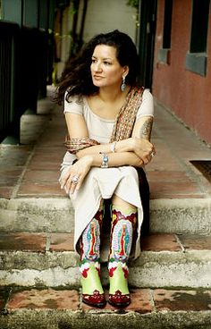 a woman sitting on the steps with her legs crossed wearing colorful socks and green boots