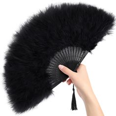 a hand holding a fan with black fur on it