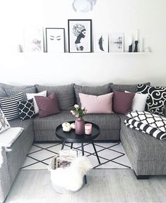 a living room with grey couches and pillows on the floor, white walls and wooden floors