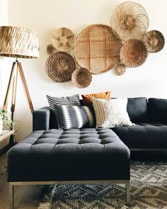 a living room with black couches and baskets on the wall