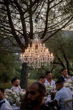 a group of people sitting around a table under a chandelier