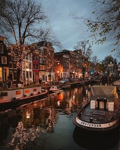 a boat is docked in the water next to some houses and trees at night time