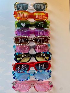 a stack of sunglasses with the words kiss me written on them and beaded glasses attached to each pair