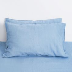 two blue pillows sitting on top of a bed