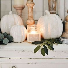 a candle is sitting on top of a dresser next to some candles and greenery