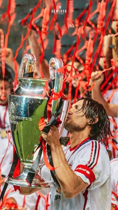 a soccer player is holding the trophy in front of his face and confetti around him