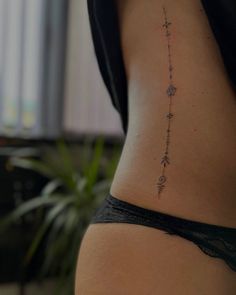 the back of a woman's stomach with an arrow and stars tattoo on it