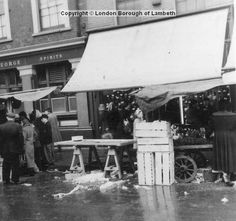 an old black and white photo of people standing in front of a booth on the street