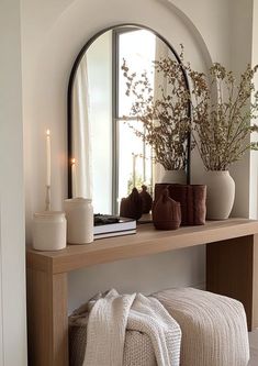 a mirror sitting on top of a wooden shelf next to a vase filled with flowers