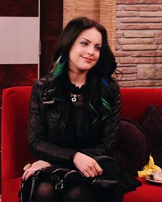 a woman with green hair sitting on a red couch