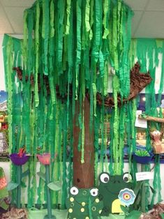 a tree made out of green tissue paper with eyes and hands on the branches, surrounded by other items