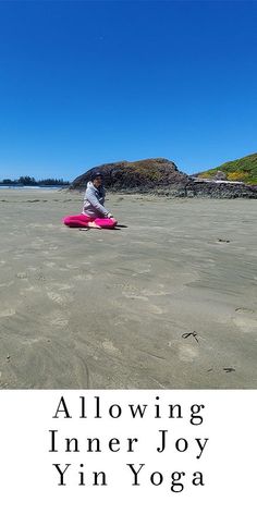 a woman sitting on top of a pink surfboard in the middle of a sandy beach