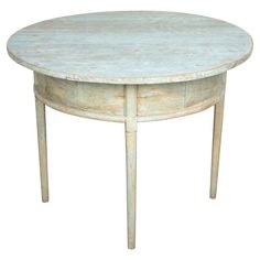 an old white table with two legs and a round top that has peeling paint on it